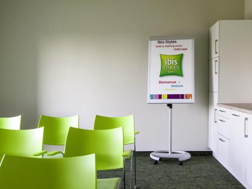 a meeting room with green chairs and a sign at ibis Styles Zeebrugge in Zeebrugge