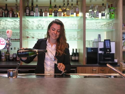 a woman pouring a glass of wine in a bar at ibis Styles Zeebrugge in Zeebrugge