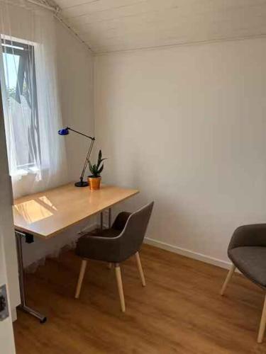 a desk with a lamp and two chairs in a room at Stylish Cottage Near Beach, Cliffs & Harbour in Havnelev