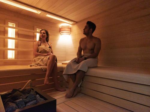 a man and a woman sitting in a sauna at ibis Styles Zeebrugge in Zeebrugge