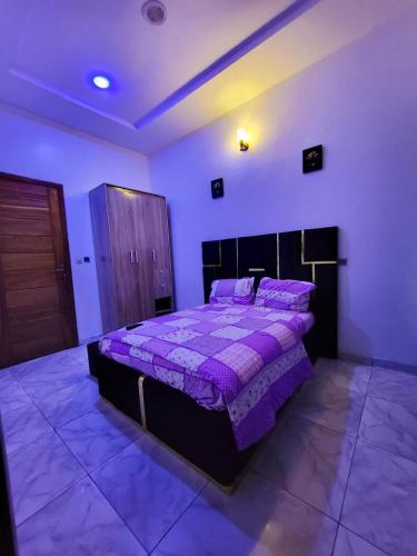 una camera da letto con un letto con un piumone viola di Lunar a Mama