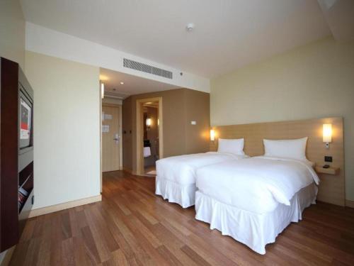 a bedroom with two beds with white sheets and wood floors at Ibis Riyadh Olaya Street in Riyadh