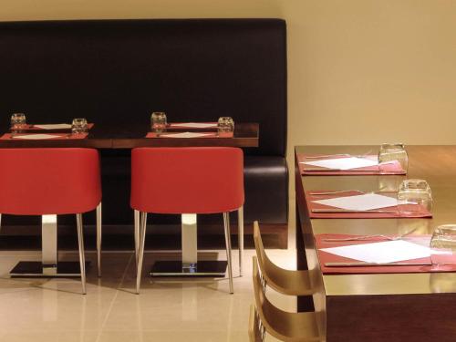 a dining room with two tables and two red chairs at Ibis Riyadh Olaya Street in Riyadh