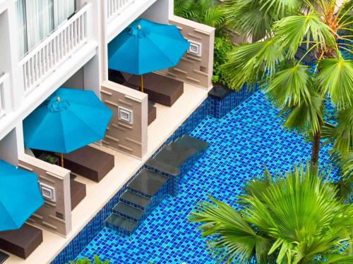 an overhead view of a pool with chairs and umbrellas at Grand Mercure Phuket Patong in Patong Beach