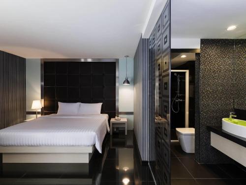 ein Schlafzimmer mit einem Bett und ein Badezimmer mit einer Badewanne in der Unterkunft ibis Styles Chiang Mai in Chiang Mai