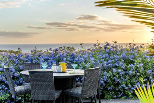 Una mesa y sillas frente a flores azules. en Ocean View Villa Sunset Pool King's Luxury experience, en Kailua-Kona