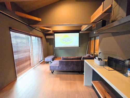 a living room with a couch and a projection screen at Relaxing箱根彫刻の森ーサウナ付き一棟貸しの宿 in Hakone
