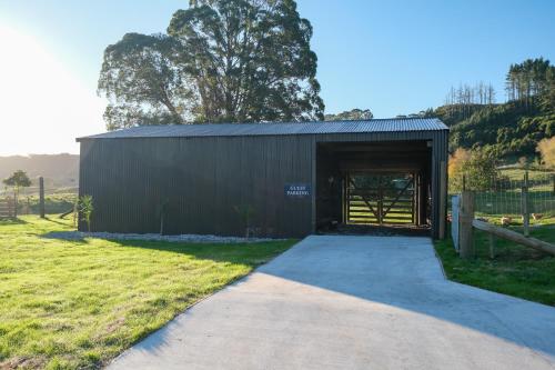 a black building with a door in a field at Hamurana Lakeview Farmhouse Luxury Retreat in Hamurana