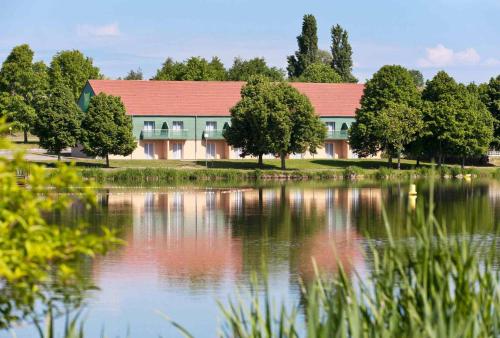 a building with a red roof next to a lake at ibis Styles Bourbon Lancy in Bourbon-Lancy