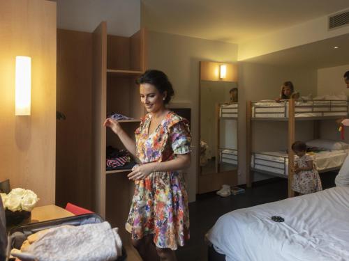 a woman is standing in a room with a bed at ibis De Panne in De Panne