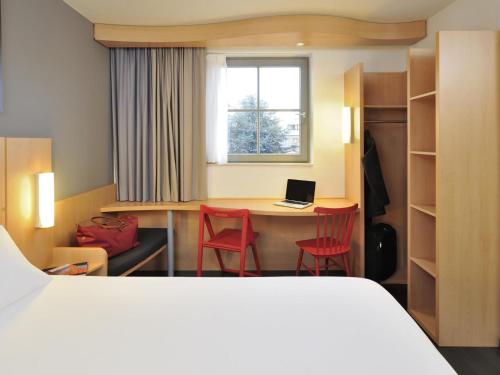 a hotel room with a bed and a desk with a laptop at ibis De Panne in De Panne