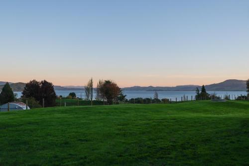 a green field with a view of the water at Hamurana Lakeview Farmhouse Luxury Retreat in Hamurana