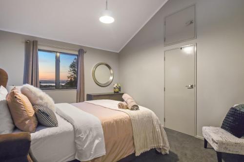 a bedroom with a bed and a chair and a window at Hamurana Lakeview Farmhouse Luxury Retreat in Hamurana