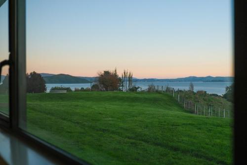 a view from a window of a green field and water at Hamurana Lakeview Farmhouse Luxury Retreat in Hamurana