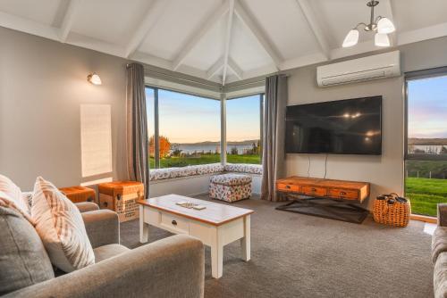 a living room with a couch and a tv at Hamurana Lakeview Farmhouse Luxury Retreat in Hamurana