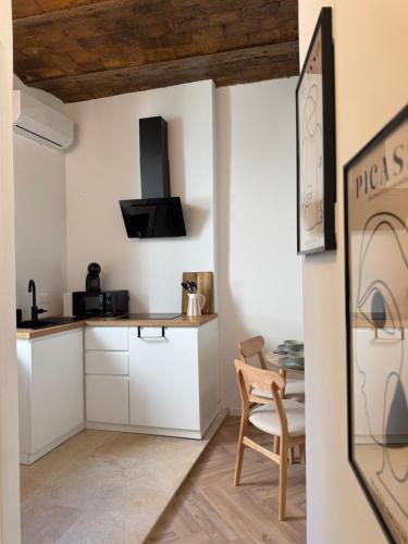 a kitchen with white cabinets and a wooden chair at Le Cloître du Palais - Studio in Avignon