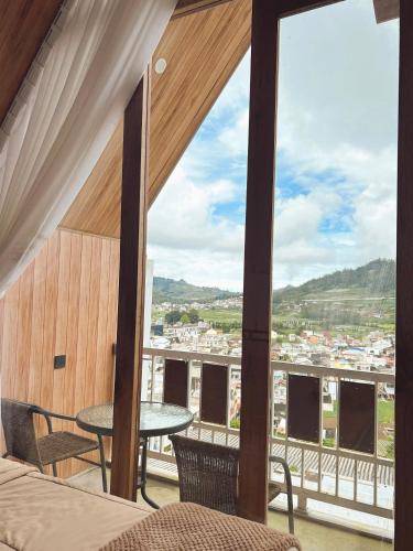 a room with a large window with a table and chairs at Sun Farm Dieng Villas in Dieng