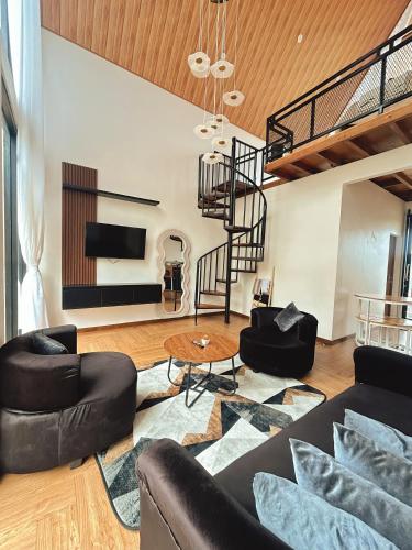 a living room with black furniture and a spiral staircase at Sun Farm Dieng Villas in Dieng