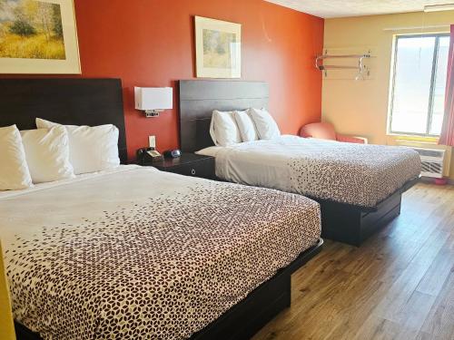two beds in a hotel room with orange walls at Budgetel inn & Suites in Fort Scott