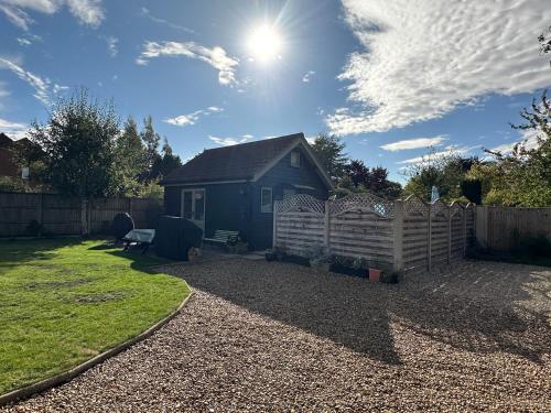 a blue house in a yard with a fence at Saving Grace with private hot tub in Bawdeswell