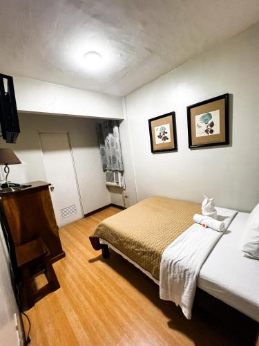a small room with two beds and a television at Stone House Hotel Manila in Manila