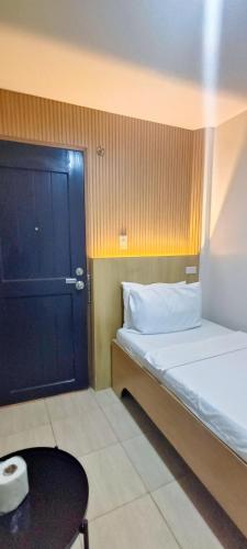 a small room with a bed and a black door at Stone House Hotel Manila in Manila