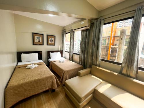 a room with two beds and a couch and a window at Stone House Hotel Manila in Manila