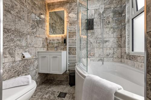 a bathroom with a tub and a toilet and a sink at Imperial Inn Studios in London