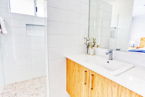 Un baño blanco con lavabo y espejo. en Casa de Reis - Beach House, en Dunsborough