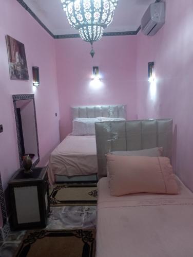 Habitación de color rosa con 2 camas y espejo. en RIAD El YacouT, en Marrakech