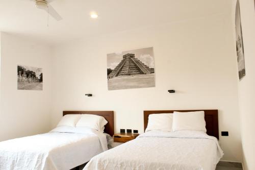 two beds in a room with white walls at Hotel Casa Vivaldi in Mérida