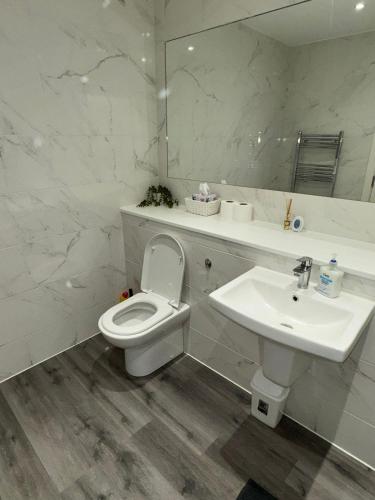 a white bathroom with a toilet and a sink at Ideal Heathrow Base 2BR 2BA Apt in Hounslow in Hounslow