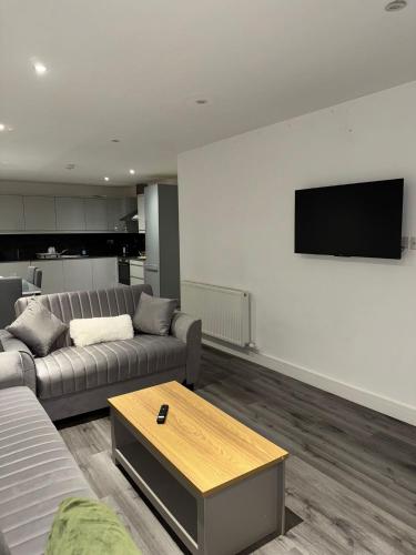 a living room with a couch and a tv on a wall at Ideal Heathrow Base 2BR 2BA Apt in Hounslow in Hounslow