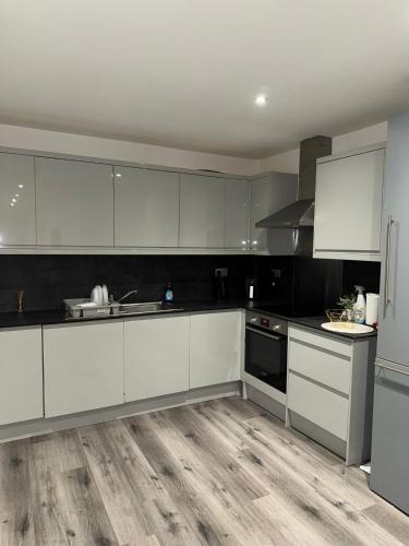 a kitchen with white cabinets and black appliances at Ideal Heathrow Base 2BR 2BA Apt in Hounslow in Hounslow