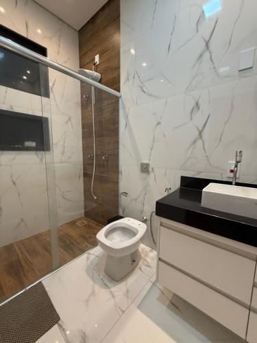 a bathroom with a toilet and a shower and a sink at Sua casa em Orlândia in Orlândia