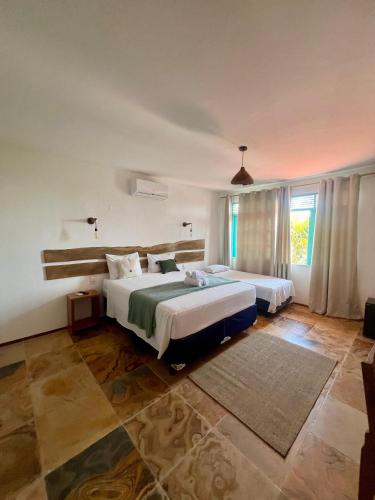 a bedroom with two beds and a large window at Bosque Cumbuco Pousada in Cumbuco