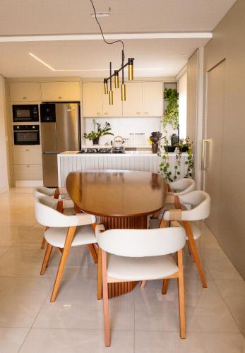 a kitchen with a wooden table and white chairs at Apartamento Alto Padrão com Vista Para o Lago in Cascavel