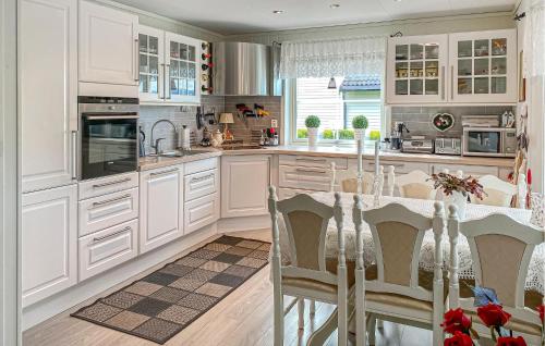 a kitchen with white cabinets and a table with chairs at Stunning Home In Skåla With House A Panoramic View in Røvik