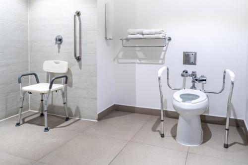a bathroom with a toilet and a chair in it at Holiday Inn Express & Suites Puebla Angelopolis by IHG in Puebla