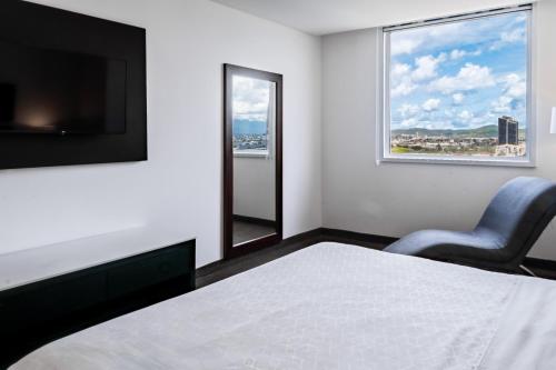 a bedroom with a bed and a chair and a window at Holiday Inn Express & Suites Puebla Angelopolis by IHG in Puebla