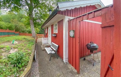 a red shed with a grill and a bench outside at Cozy Home In Läckeby With Wifi in Bäckebo