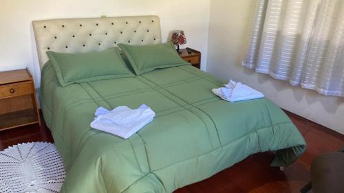 a green bed with two towels on top of it at Pousada Perrone Antiga pousada Marins in Campos do Jordão