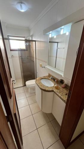a bathroom with a sink and a toilet and a mirror at Apto CAPAO DA CANOA Ed GABRIELA 6 Pers in Capão da Canoa