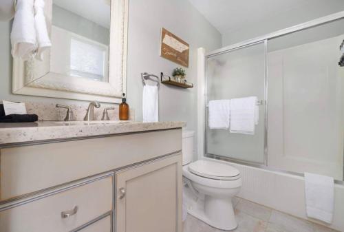 a white bathroom with a toilet and a shower at Relaxing Lakefront Retreat w/ Hot Tub & Dock in Blountville