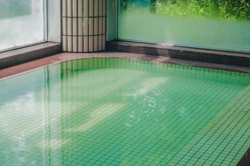 a swimming pool in a building with green tiles at Oehonke in Kitami