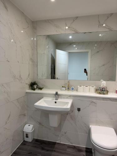 a white bathroom with a sink and a mirror at Spacious 3BR Stay Near Heathrow and Central London in Hounslow