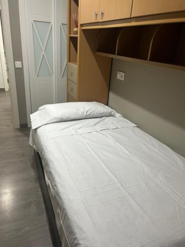 Cama blanca en habitación con armario en Melilla, en Melilla