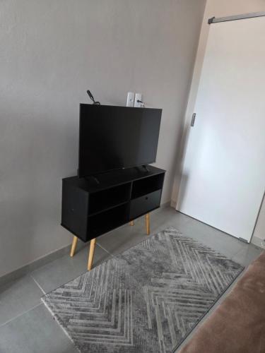 un centro de entretenimiento negro con TV de pantalla plana en la parte superior en Kitnets da Dona Val, en Joinville
