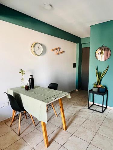 a dining room table with chairs and a clock on the wall at Altos de Barrio Sur in San Miguel de Tucumán