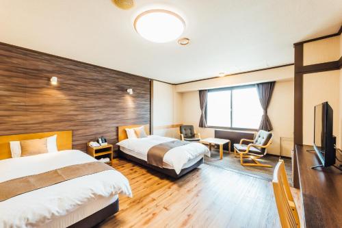 a hotel room with two beds and a flat screen tv at Oehonke in Kitami
